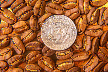 Roasted coffee beans with a dime for scale on a golden backdrop, emphasizing their warm brown...