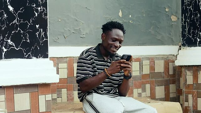 excited black African man using mobile phone for sending and receiving messages