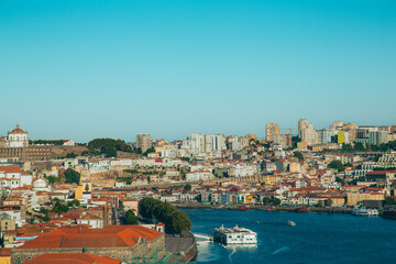 Panoramic view of Porto cityscape from gardens of Palacio de Cristal with traditional houses, Douro river with boats navigating and Serra do Pilar Monastery on a sunny day with blue sky. Portugal.