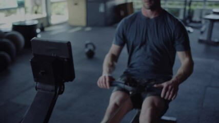 Focused man using rowing machine in gym for effective workout session - Powered by Adobe