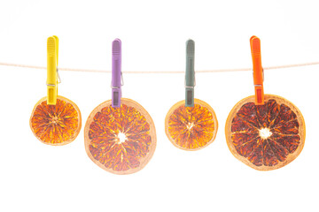 dried pieces of different citrus fruits hang on colored clothespins