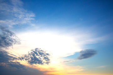 Dramatic sunset sky featuring golden, fiery clouds against a deepening blue background. The rich colors and dynamic cloud formations create a stunning natural display.