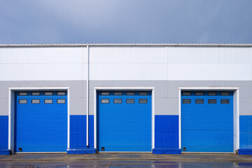 Row of overhead sectional gates in a multi-seat cargo truck garage. Outdoors front view.