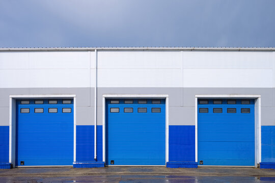 Row of overhead sectional gates in a multi-seat cargo truck garage. Outdoors front view.