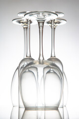 Five crystal-clear wine glasses with varied shapes stand in a row, their reflections shimmering on...