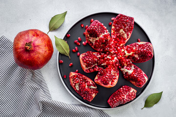 Top view of fresh ripe pomegranate and pieces on plate for eating, top view.