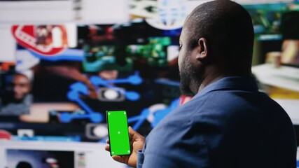 Professional media expert in a high tech space holds green screen, leveraging social media, internet big data and cloud systems. Person engaging followers to boost digital presence. Camera A.