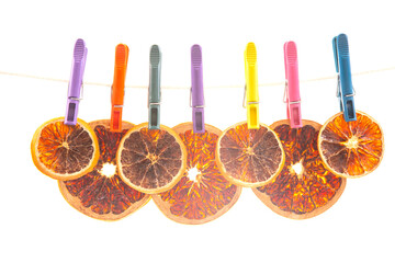 dried pieces of different citrus fruits hang on colored clothespins