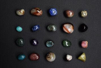 Background of beautiful natural colored semi-precious stones. Purple amethyst, agate, labradorite, jasper, kyanite, lapis lazuli on a dark background close-up.