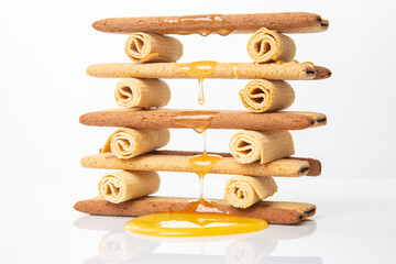 Fresh flower honey flows and drips onto herdry crispy cookie sticks. Dessert snack food.
