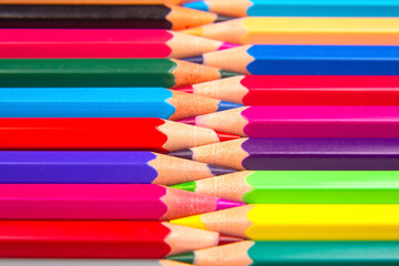 Fototapeta premium Colorful pencils in a stacked grid pattern against a white surface. Ideal for art, education, and design themes with a bright and dynamic visual appeal.