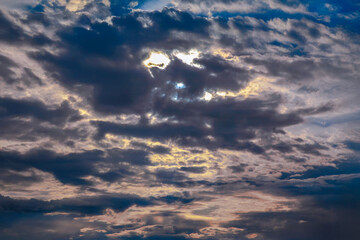 Sunset sky with layered clouds in various shades of blue, gray, and gold. A mesmerizing display of nature’s beauty, perfect for backgrounds or atmospheric concepts.