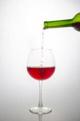 Dynamic shot of a green bottle pouring vibrant red wine into a delicate glass, with effervescent...
