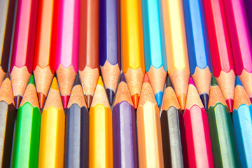 Brightly colored pencils in a layered grid arrangement against a white surface. Ideal for promoting...