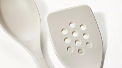 Kitchen utensils include a slotted spatula and a serving spoon designed for versatile cooking and baking purposes.