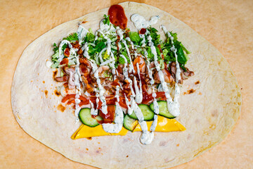 Colorful tortilla wrap filled with fresh ingredients and savory toppings ready to be rolled