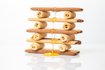 Fresh flower honey flows and drips onto herdry crispy cookie sticks. Dessert snack food.