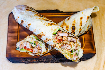 Delicious grilled chicken wrap with fresh vegetables served on a wooden board in a cozy cafe setting