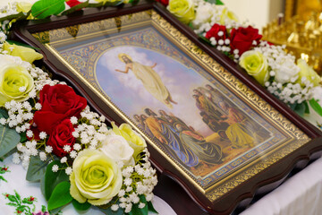 Religious ceremony featuring a beautifully decorated icon surrounded by fresh flowers in a serene...