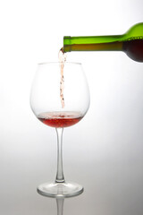 Dynamic shot of a green bottle pouring vibrant red wine into a delicate glass, with effervescent...