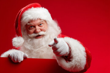 Naklejka premium Santa Claus Pointing at Blank Space for Advertisement or Banner on Colorful Background
