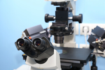 A scientist in a blue cap examines a sample under a high-tech microscope in a lab, with a petri...