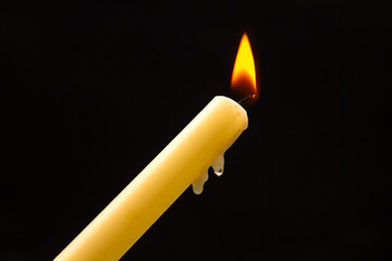 Lighting a candle with a wooden match on a dark background. Burning candle fire