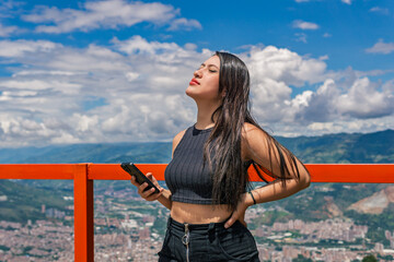 Young Colombian woman enjoying sunlight at scenic viewpoint over Medellin