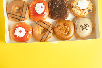 A variety of colorful donuts arranged in a box, featuring a mix of glazed, chocolate-coated, and sprinkled toppings. The assortment includes donuts with vibrant green, white, red, and chocolate