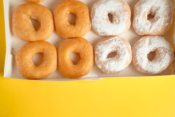 A variety of colorful donuts arranged in a box, featuring a mixture of glaze, and powdered sugar. Perfect for recipes, articles or any cooking content
