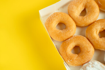 A variety of colorful donuts arranged in a box, featuring a mixture of glaze, and powdered sugar. Perfect for recipes, articles or any cooking content