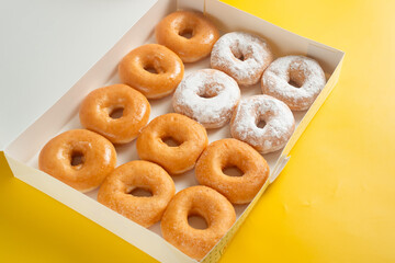 A variety of colorful donuts arranged in a box, featuring a mixture of glaze, and powdered sugar. Perfect for recipes, articles or any cooking content