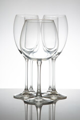 Elegant wine glasses with long stems and clear bowls, arranged in a line with reflections on a shiny surface, perfect for luxury dining or celebration themes.