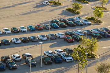 Aerial view of dealership parking lot with many brand new cars for sale. Development of american...