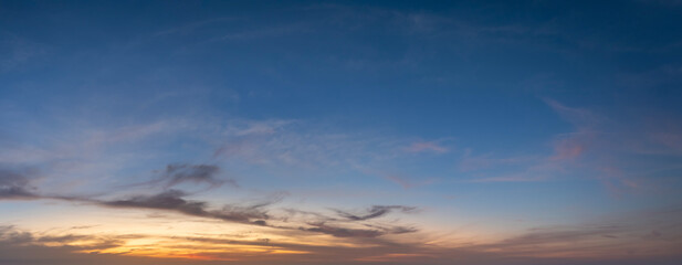 Colorful sunset sky with setting sun behind vivid orange and yellow clouds