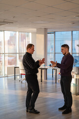 Two Caucasian men talking at work in the office. 