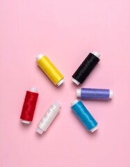 Naklejka premium Vibrant colored sewing thread spools neatly arranged on a bright pink background, creating a visually appealing pattern. Ideal for craft, hobby, and textile designs. Top view with copy space.