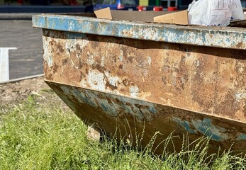 An Old and Rusty Dump Container That is Surrounded by Lush, Overgrown Grass and Weeds. A weathered...