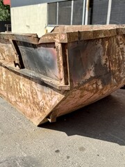 An old rusty dumpster sitting on a bustling city street filled with urban life and debris. The...