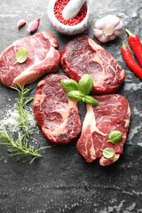 Pieces of raw beef meat and spices on dark table, flat lay