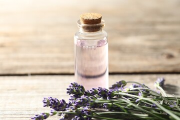 Natural essential oil and lavender flowers on wooden table, closeup