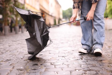 Woman with broken umbrella on wet pavement outdoors, closeup