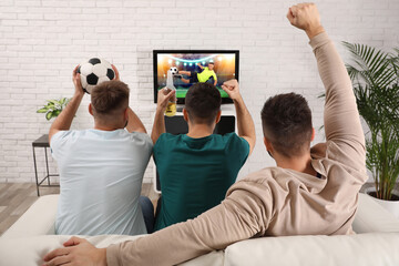 Football fans watching soccer match on TV set at home, back view