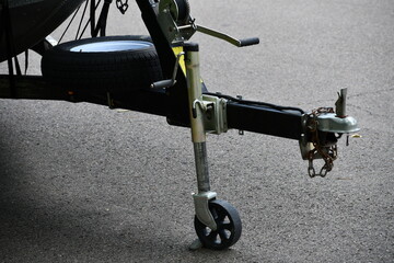Boat trailer. Adjustable post, ball hitch hookup, safety chains, spare tire, hand crank winch. Small rock blocking wheel from moving.