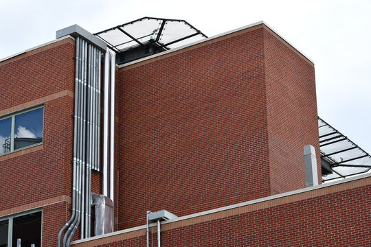 Large hospital building with large electrical conduits exposed and running up towards roof. HVAC ducting running parallel to electrical lines.