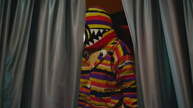 Costume color&eacute; de monstre ray&eacute; cach&eacute; dans des rideaux