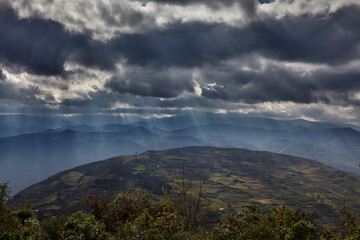 Dramatic skies over the highlands near Kuelap fortress in Amazonas, Peru. Sunbeams filter through dense clouds, illuminating the rugged landscape where the Chachapoya civilization once thrived.