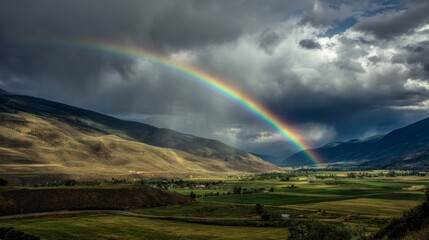 Fototapeta premium Rainbow over valley landscape