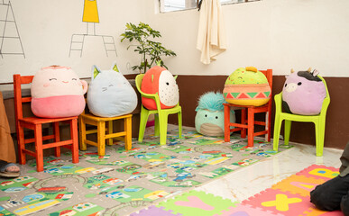 Varied stuffed toys arranged on classroom chairs as if attending a lesson in a preschool. Concept...