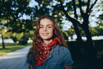Lifestyle woman in modern boho-western denim street style with a red bandana smiles outdoors under...